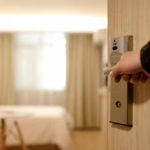 An image of a person holding the door open to a hotel room